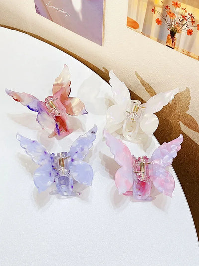 Set of four colorful butterfly hair claws made of high-quality acetate, displayed on a white table. Elegant hair accessories for long hair hold.